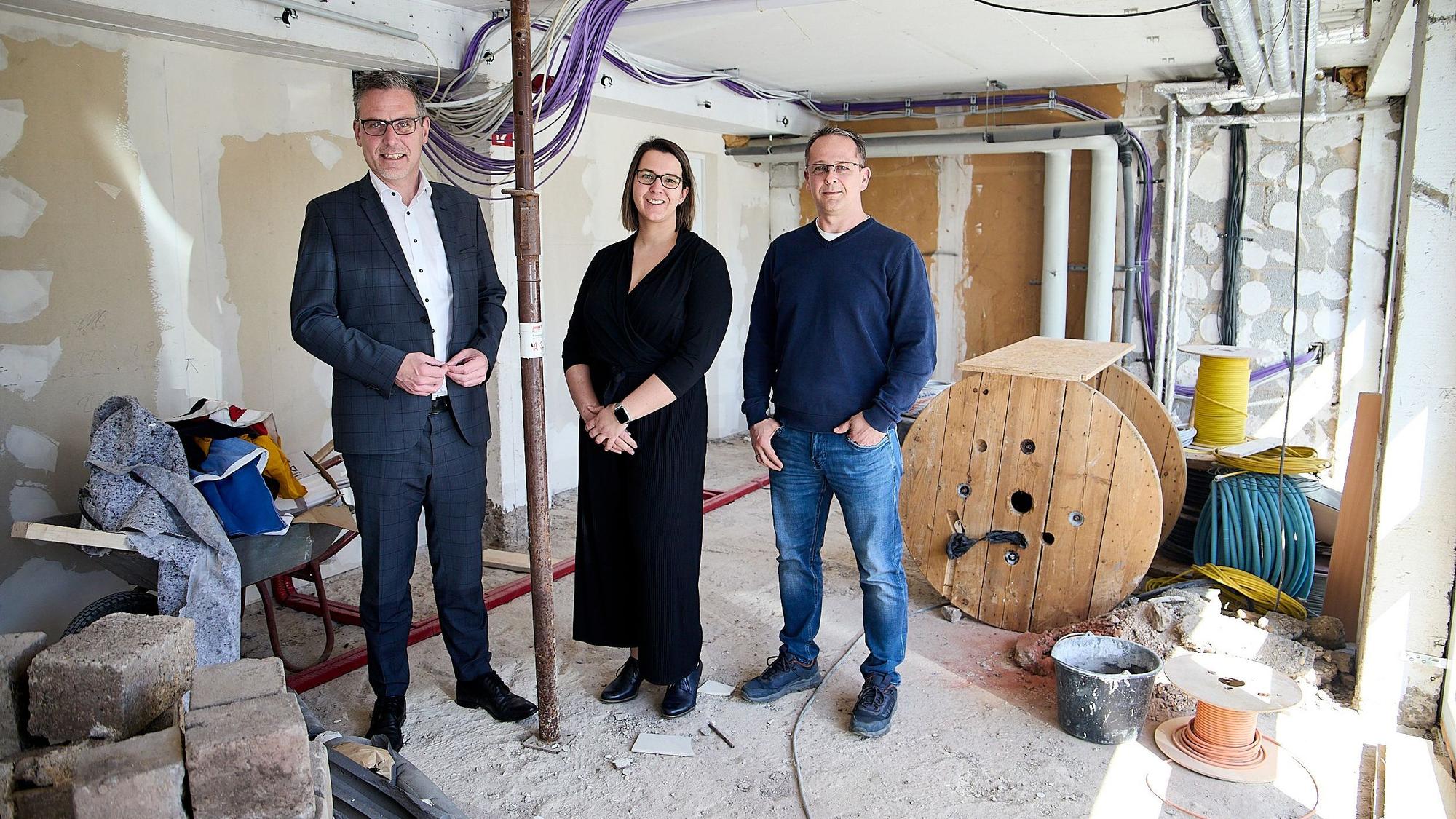 Norbert Crump, Eva Gäbler und Marco Schell stehen in einer einstigen Garage, die eine Baustelle ist.