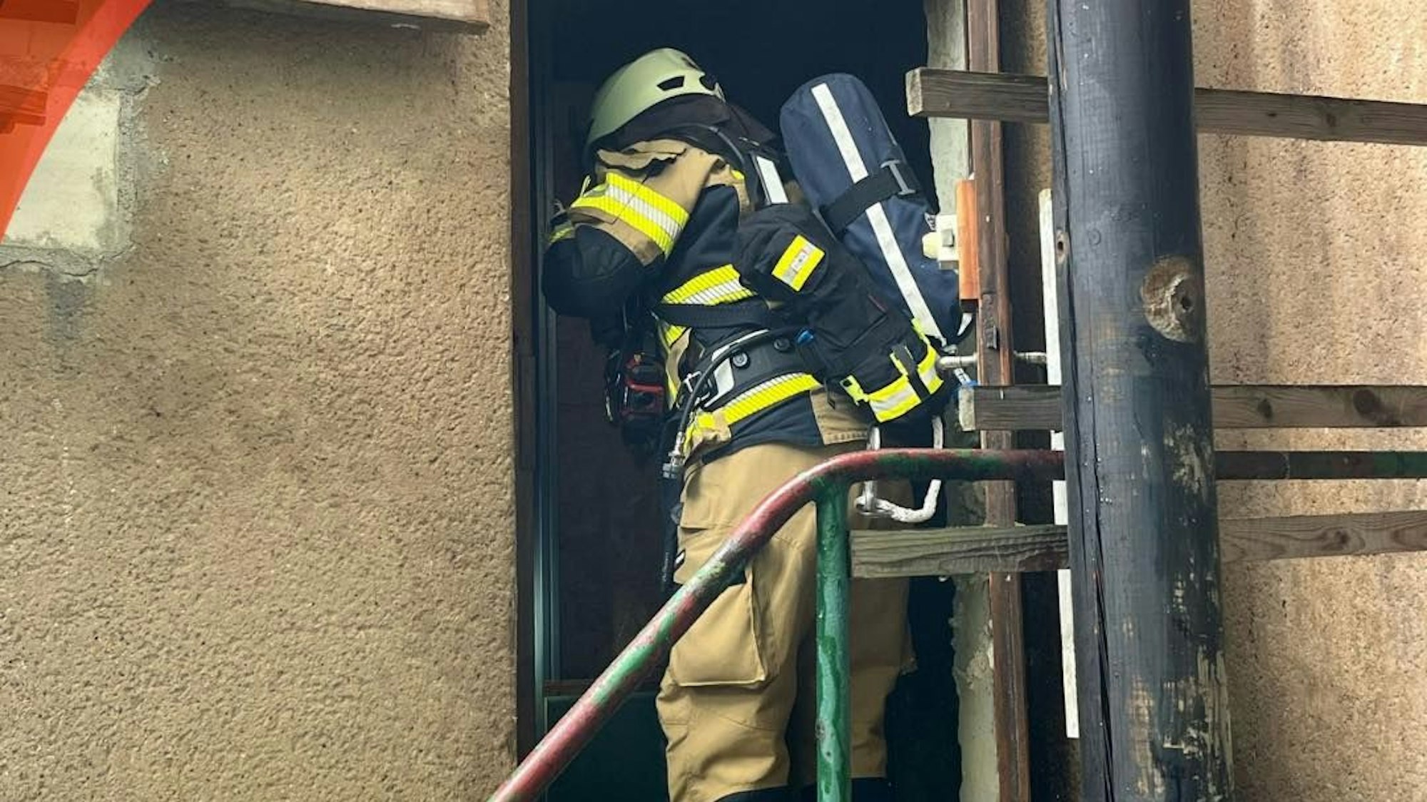 Zu sehen ist ein Feuerwehrmann in einem Hauseingang.