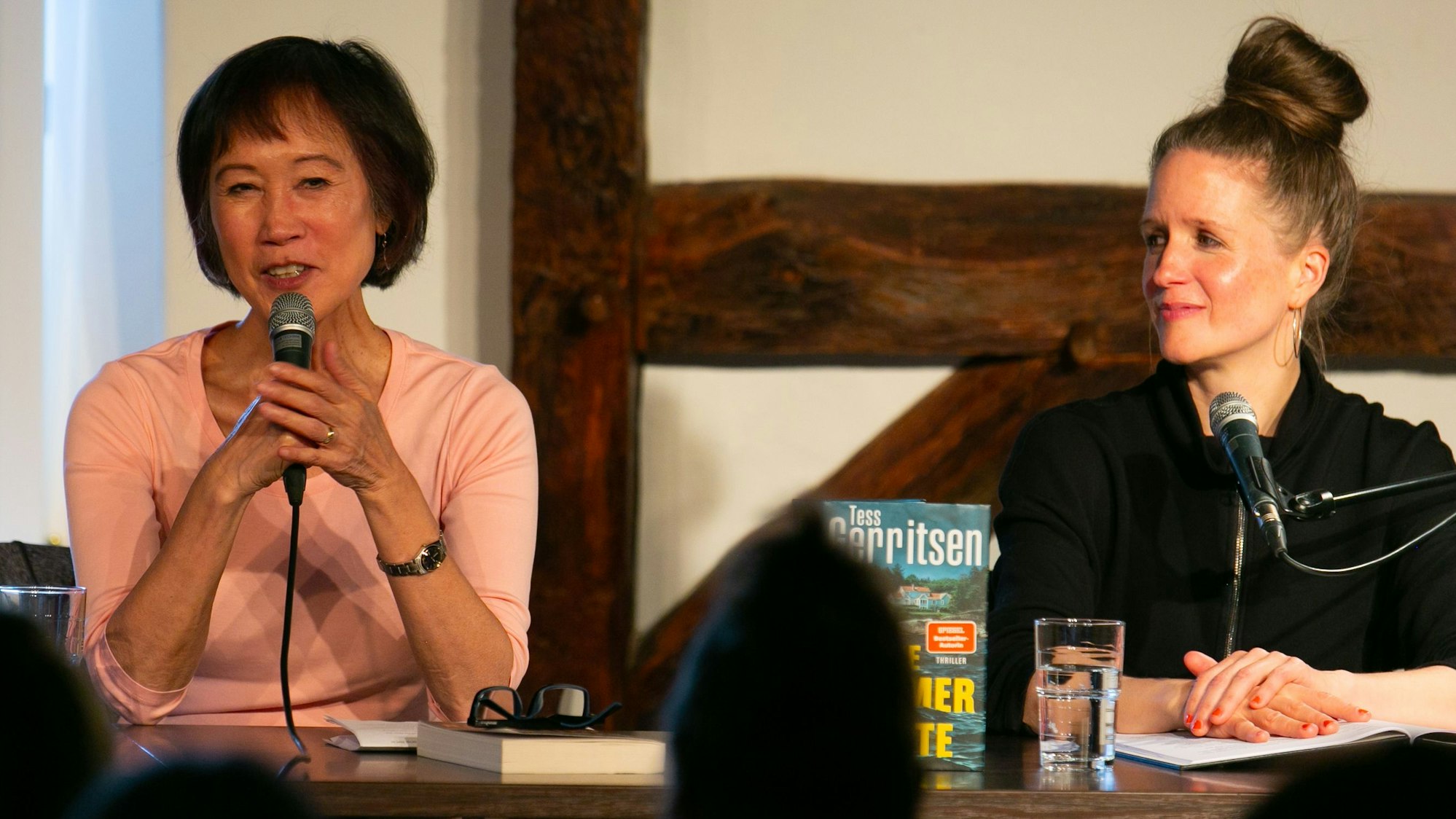 Tess Gerritsen spricht ins Mikrofon, während Julia Nachtmann lächelnd zuhört.