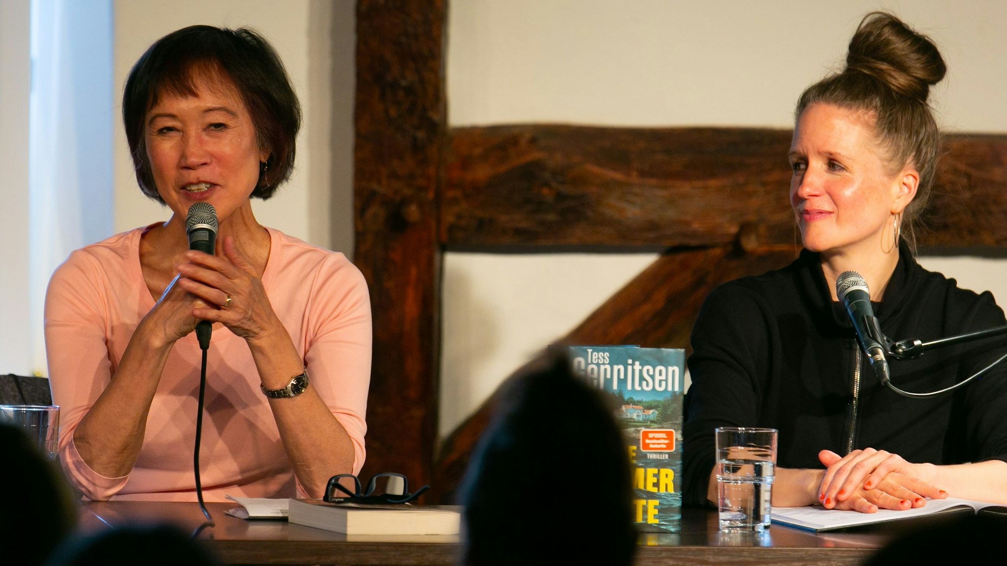 Tess Gerritsen  spricht ins Mikrofon, während Julia Nachtmann lächelnd zuhört.