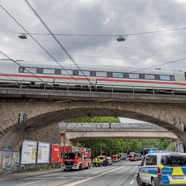 Einsatzkräfte von Polizei und Feuerwehr stehen an einer Eisenbahnunterführung am Bergischen Ring in Köln-Mülheim, auf der ein ICE liegengeblieben ist.