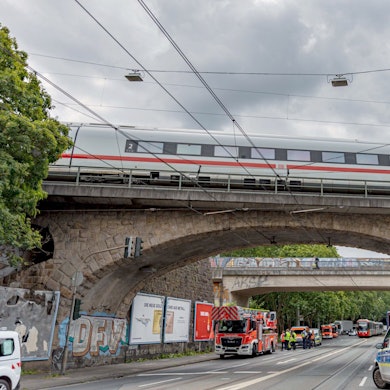 Einsatzkräfte von Polizei und Feuerwehr stehen an einer Eisenbahnunterführung am Bergischen Ring in Köln-Mülheim, auf der ein ICE liegengeblieben ist.