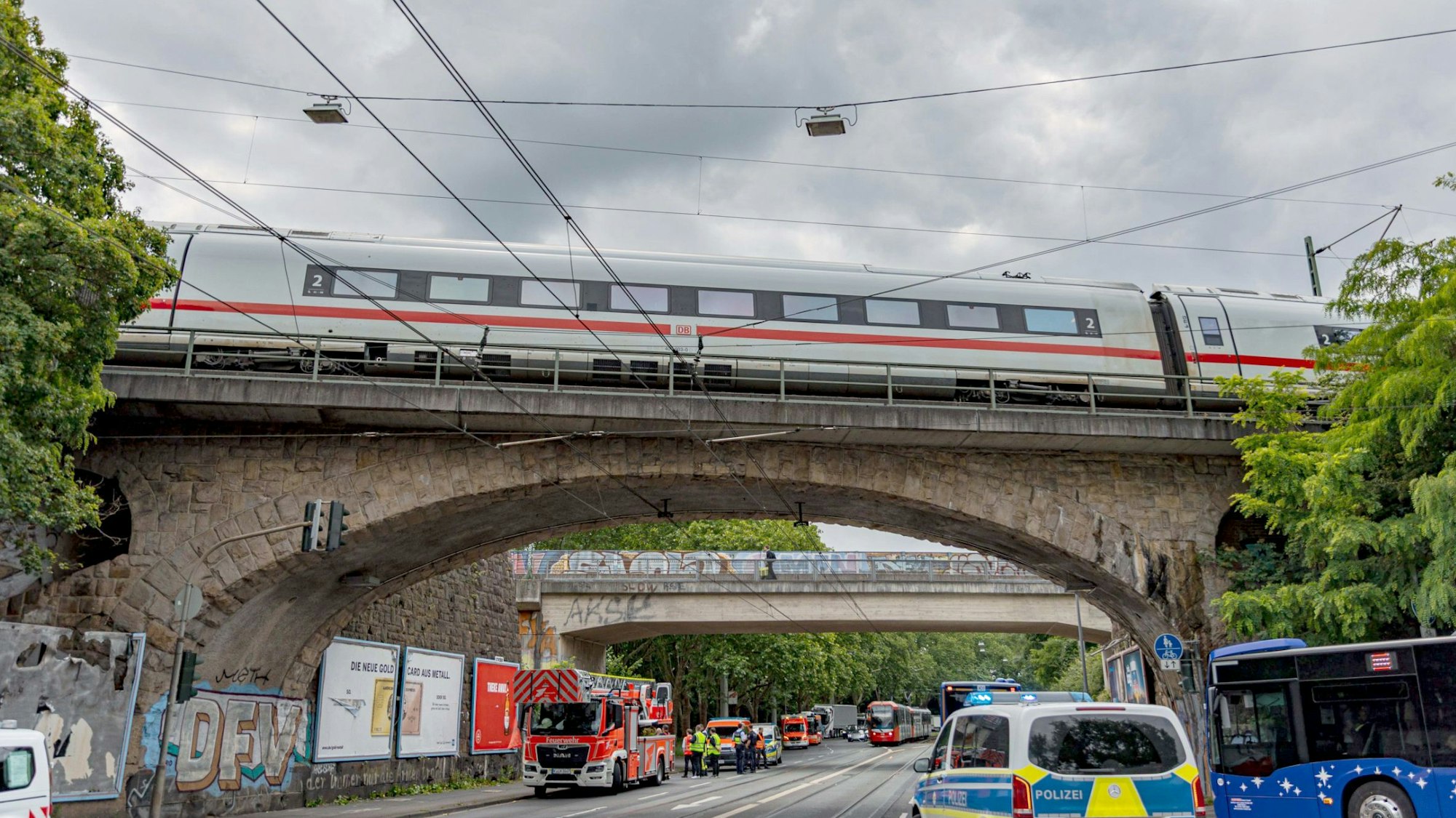 Einsatzkräfte von Polizei und Feuerwehr stehen an einer Eisenbahnunterführung am Bergischen Ring in Köln-Mülheim, auf der ein ICE liegengeblieben ist.