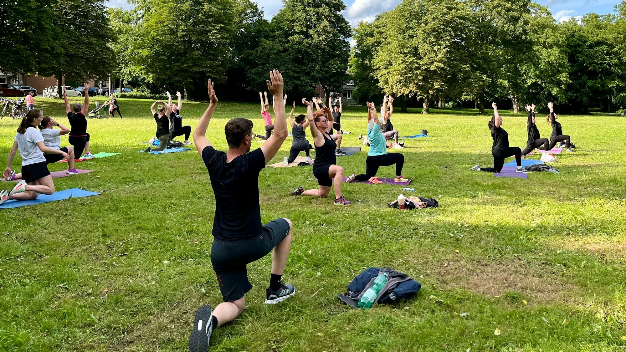 Zu sehen sind Menschen, die auf einer Wiese Sport treiben.