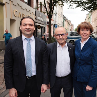 Drei Männer und eine Frau stehen nebeneinander auf einer schmalen Straße, der Keupstraße in Mülheim.
