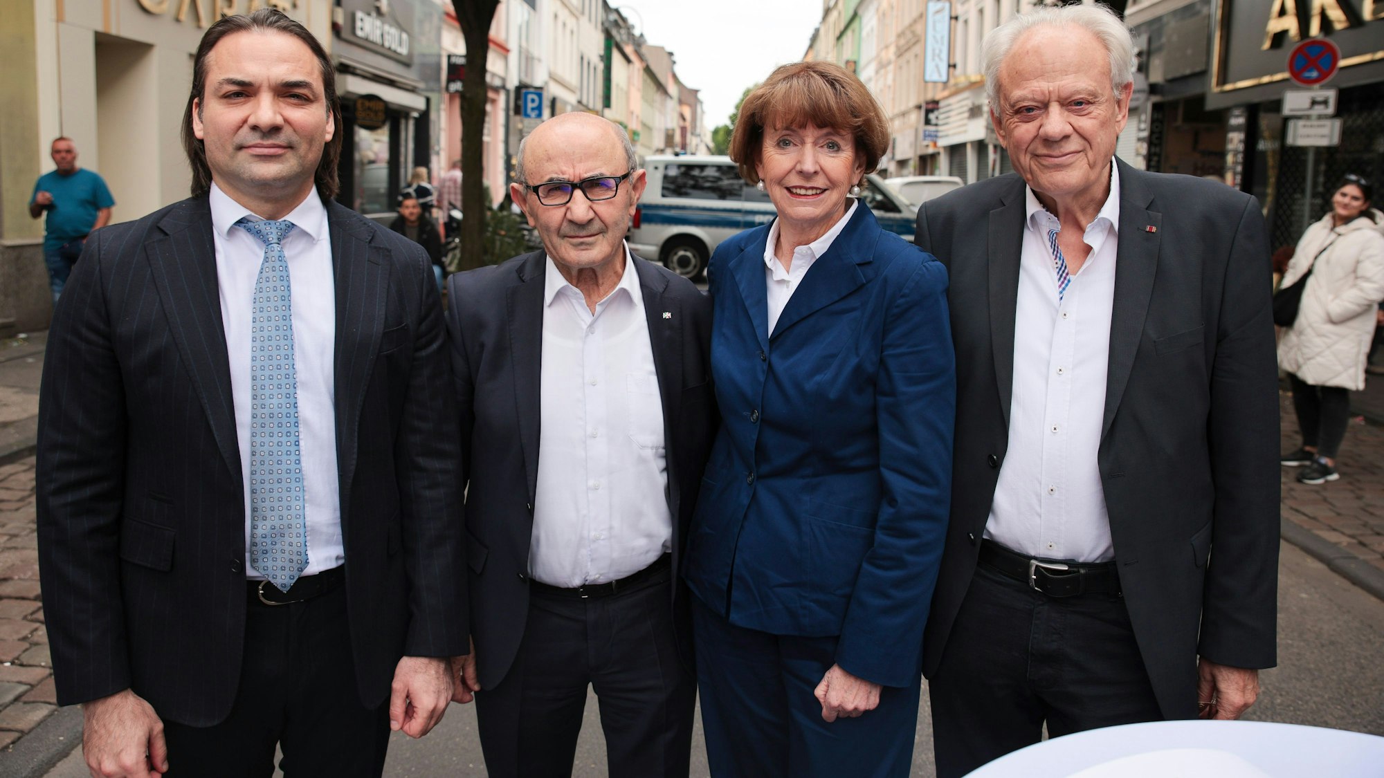 Drei Männer und eine Frau stehen nebeneinander auf einer schmalen Straße, der Keupstraße in Mülheim.