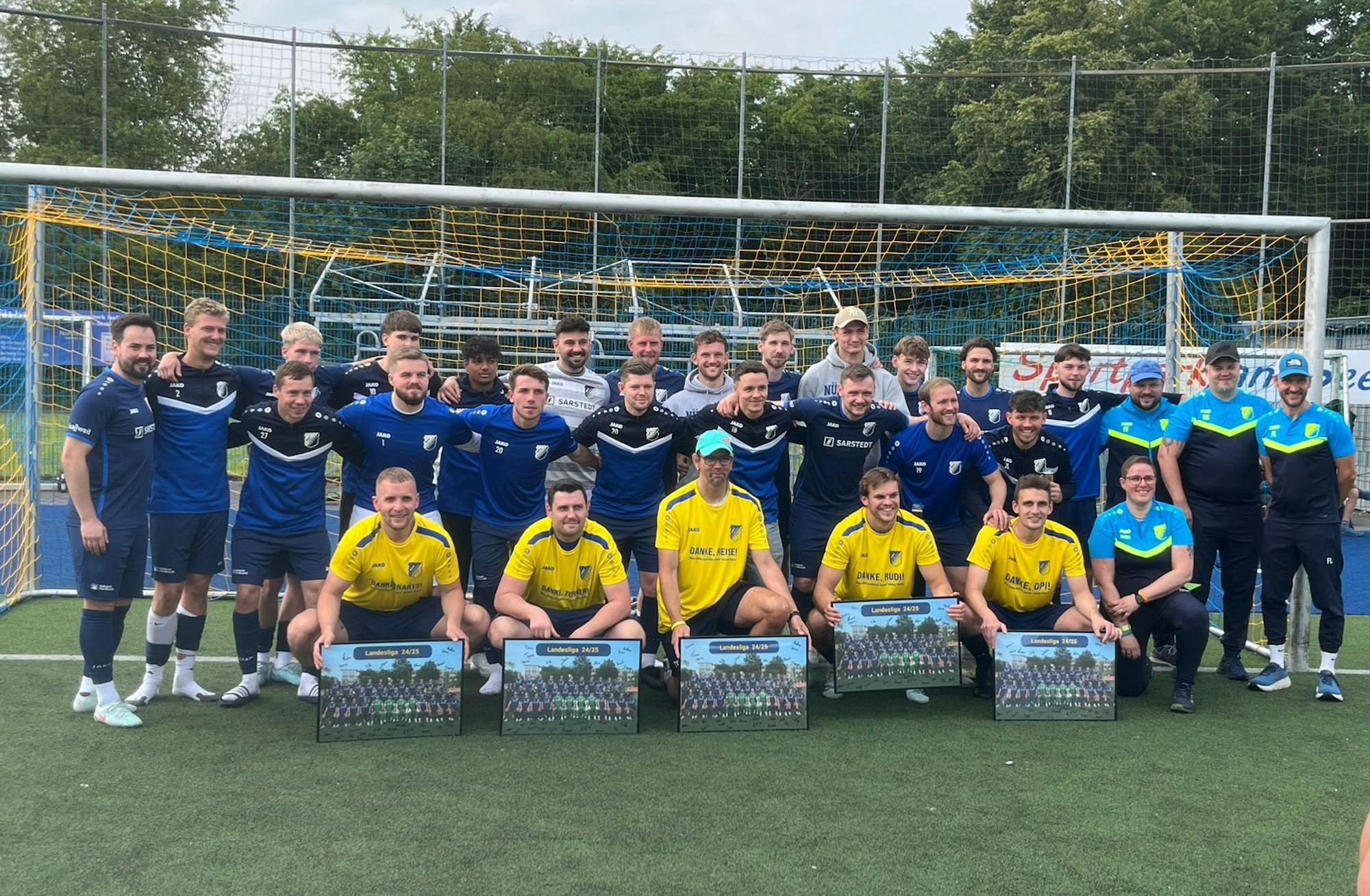 Vor der Mannschaft knieen die Spieler und der Trainer, die verabschiedet wurden.