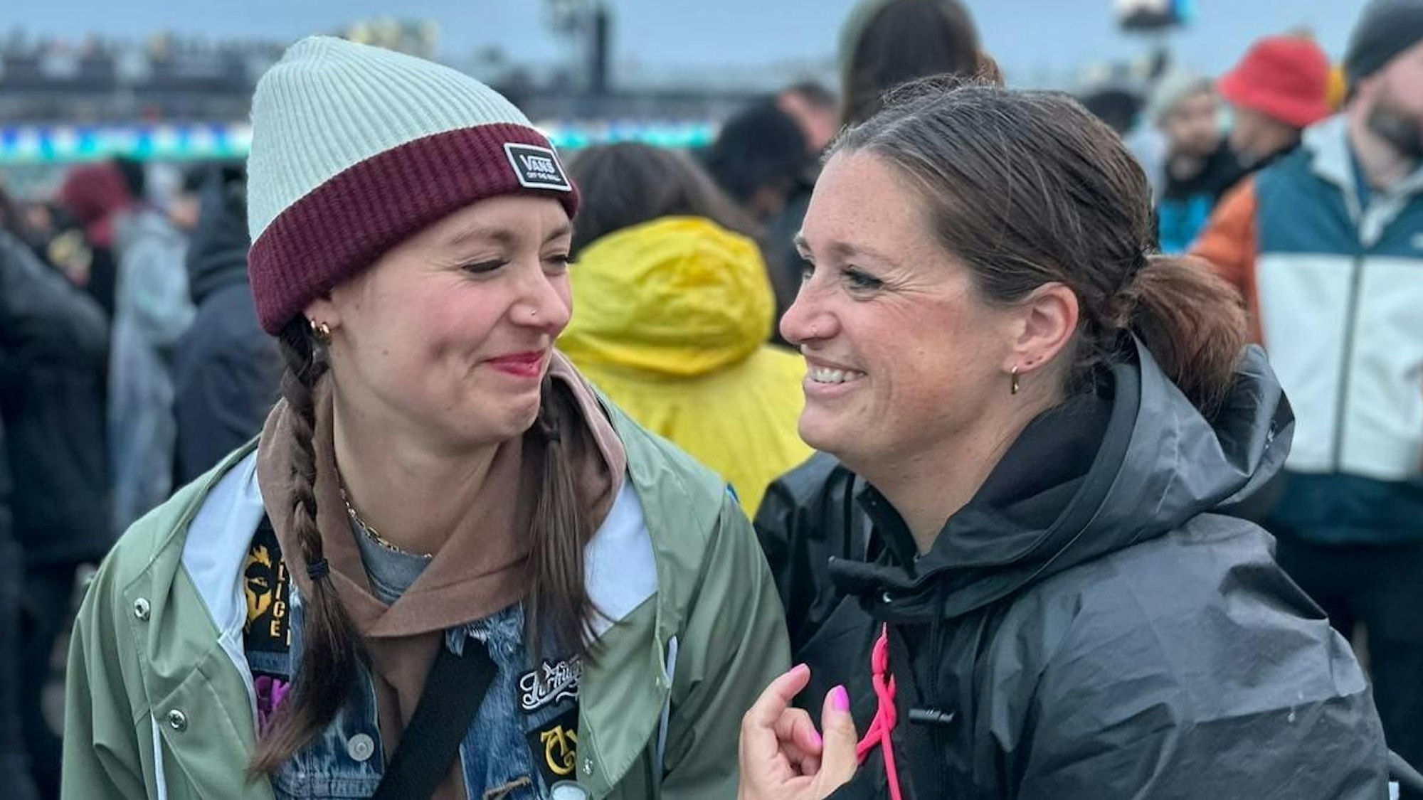 Zwei Frauen in Regenjacken schaue sich an und lachen.
