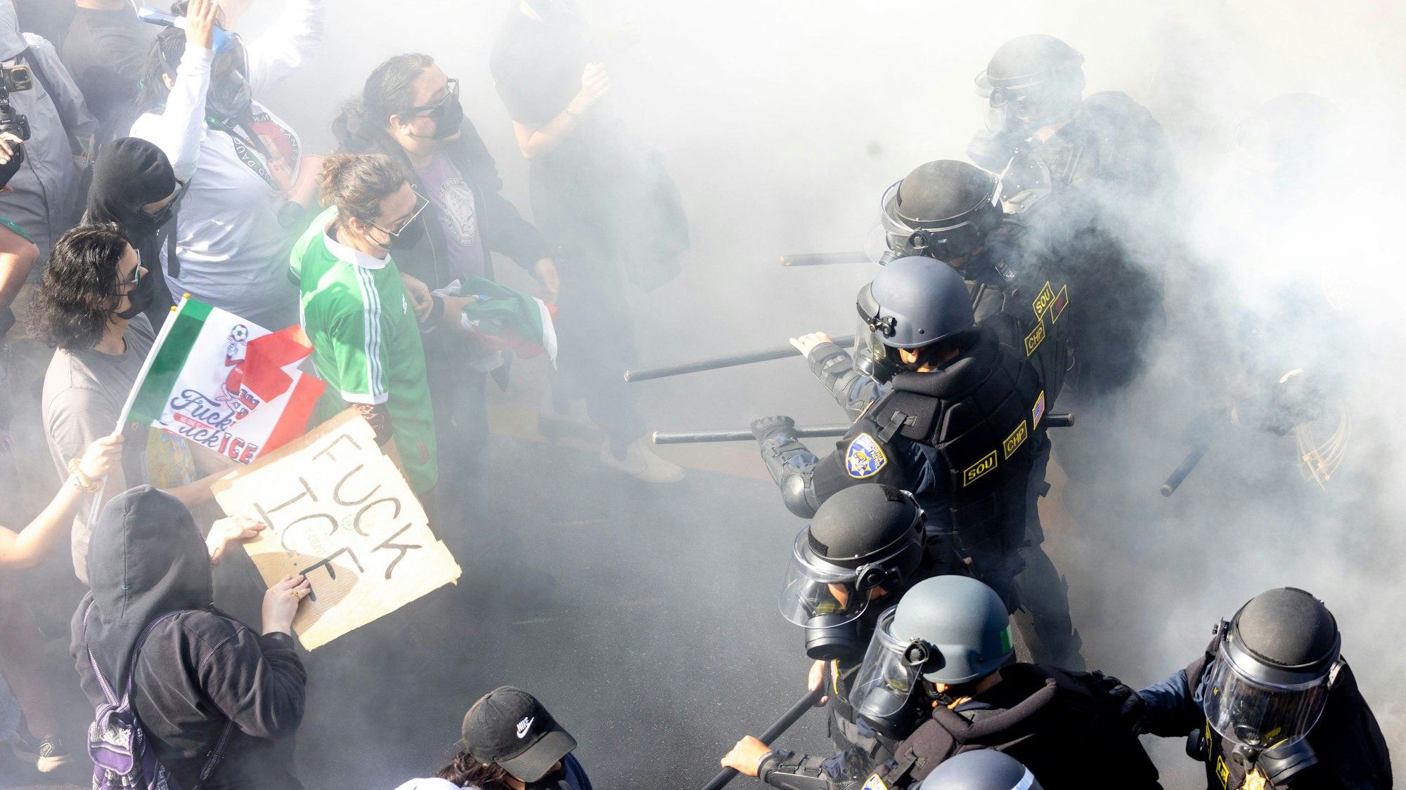 dpatopbilder - 08.06.2025, USA, Los Angeles: Rauch liegt in der Luft, als Demonstranten sich mit CHP-Beamten anlegen, nachdem sie den 101 Freeway in der Innenstadt besetzt haben, um gegen die Durchsuchung von Einwanderern zu protestieren. Foto: Jill Connelly/ZUMA Press Wire/dpa +++ dpa-Bildfunk +++