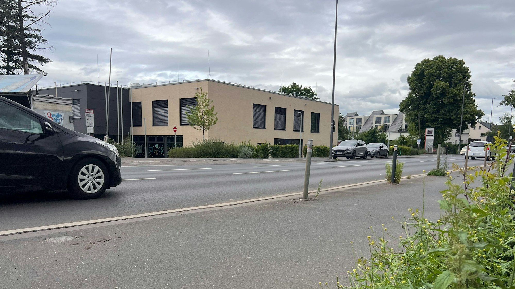 Blick auf die Siegburger Straße. Auf der gegenüberliegenden Straßenseite sieht man den beigen Neubau der Janusz-Korczak-Grundschule.