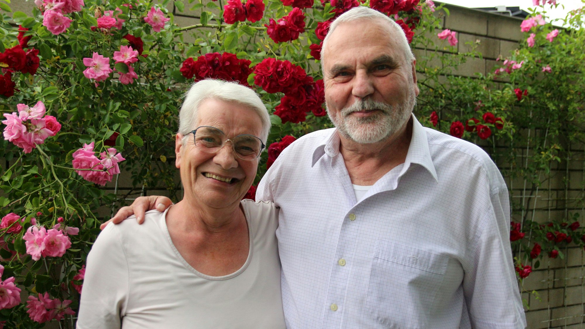 Eine Frau und ein Mann lächeln in die Kamera. Er hat einen Arm um ihre Schulter gelegt.