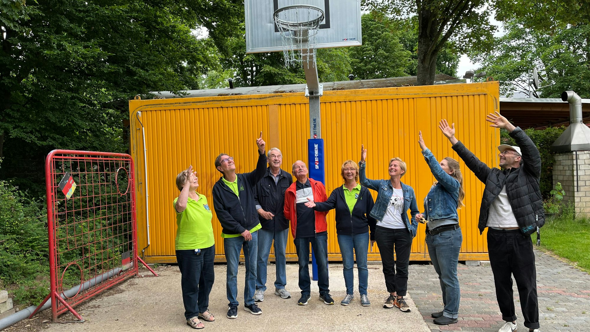 Acht Menschen stehen vor einer neuen Basketballanlage.