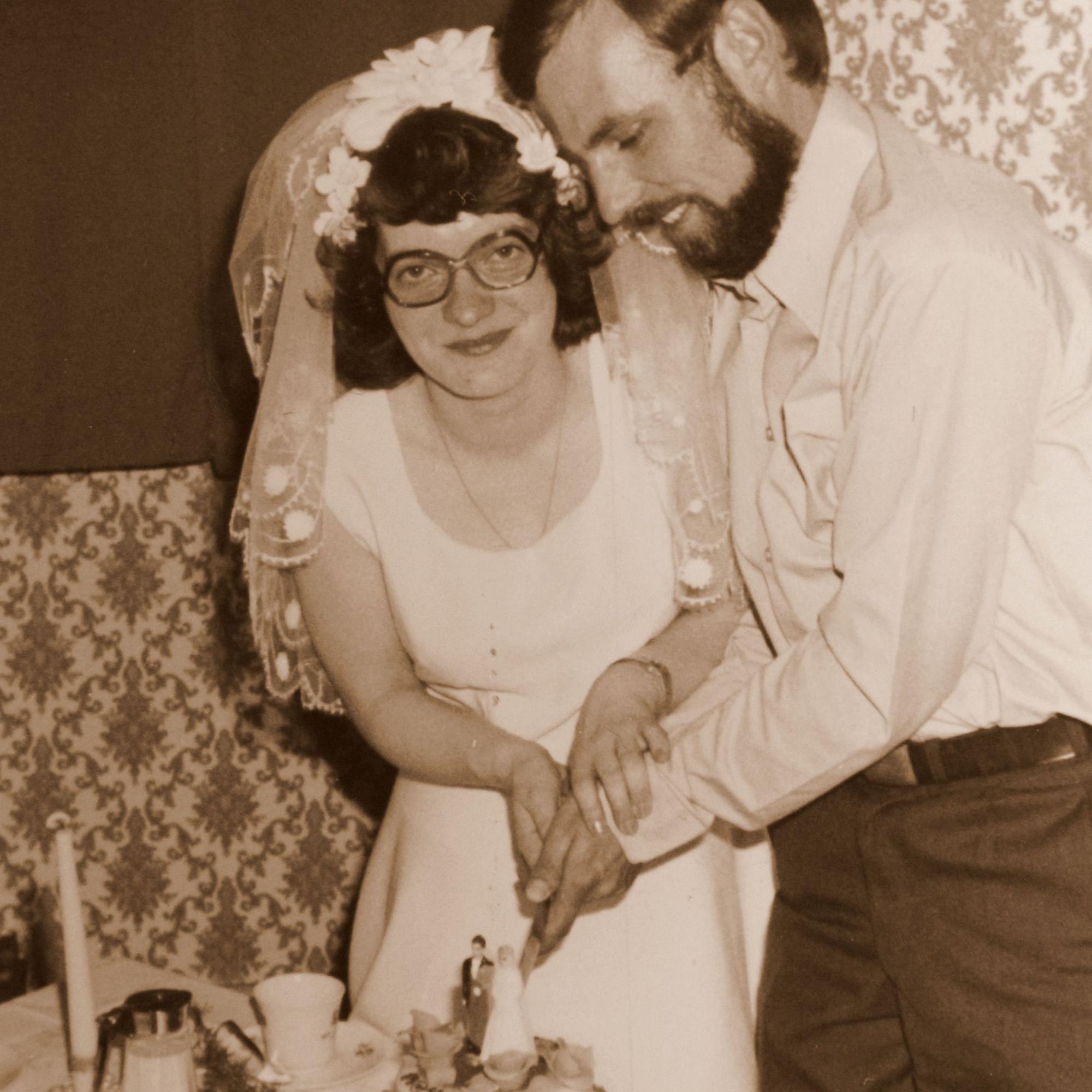 Die frisch Vermählten schneiden die Hochzeitstorte an.
