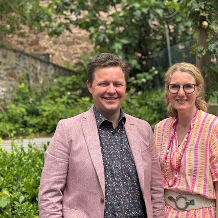 Christian Meyer trägt ein Sakko und ein gemustertes Hemd. Neben ihm steht Claudia Rapp-Ludwig in einer sommerlichen Bluse, mit einer breiten Schnalle und Ketten. Sie stehen im Grünen.