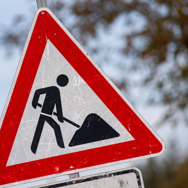 Das Bild zeigt ein zerkratztes Schild mit dem Piktogramm eines Bauarbeiters zur Beschilderung einer Baustelle.