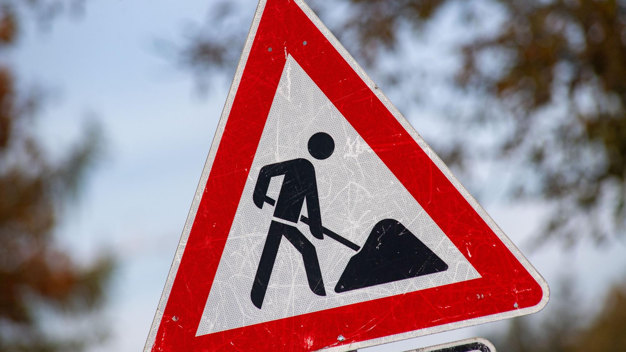 Das Bild zeigt ein zerkratztes Schild mit dem Piktogramm eines Bauarbeiters zur Beschilderung einer Baustelle.