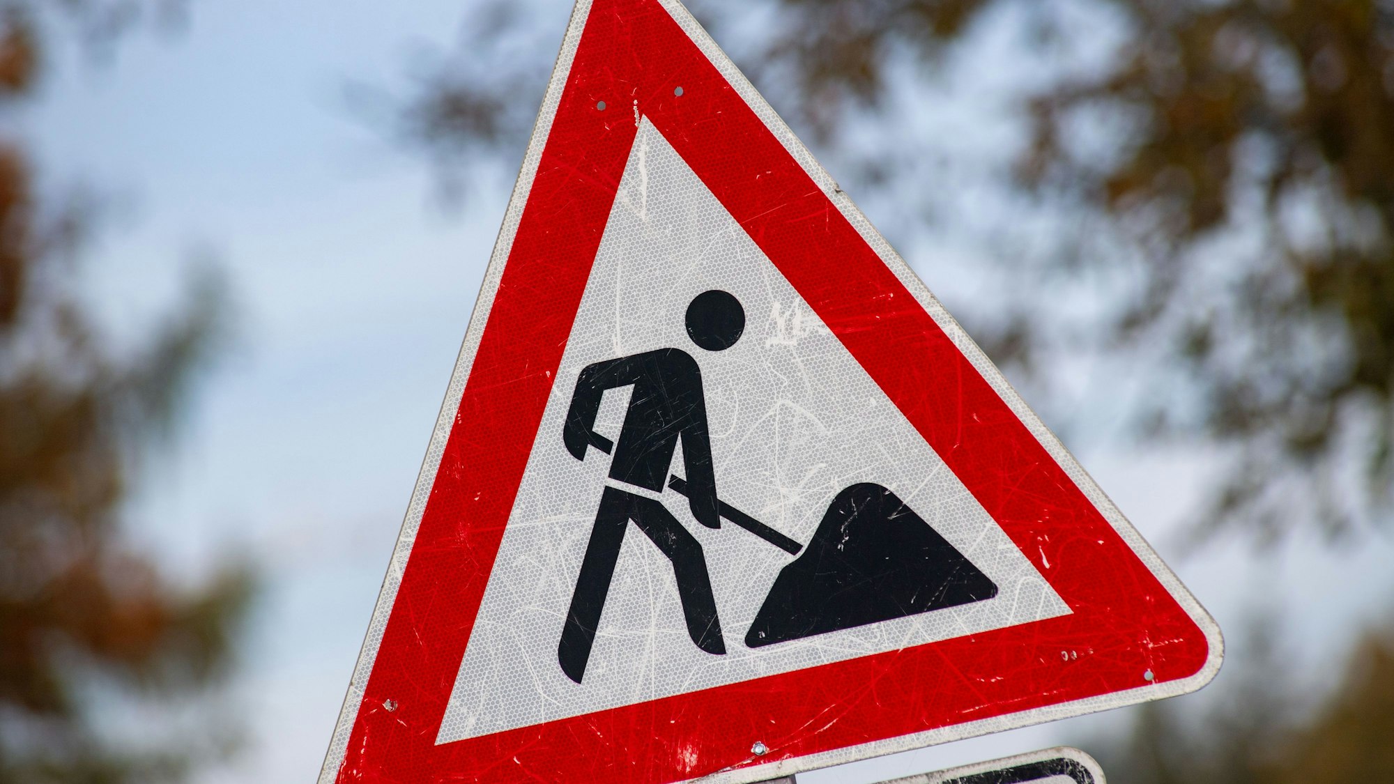 Ein zerkratztes Schild „Gefahrzeichen Arbeitsstelle“ mit dem Piktogramm eines Bauarbeiters zur Beschilderung einer Baustelle.