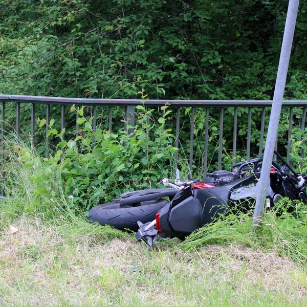 Ein verunfalltes Motorrad (Honda) liegt in einer Wiese neben einem Geländer in Odenthal-Altenberg.