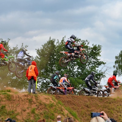 Motocross-Fahrer verlassen teil springend einen Hügel.