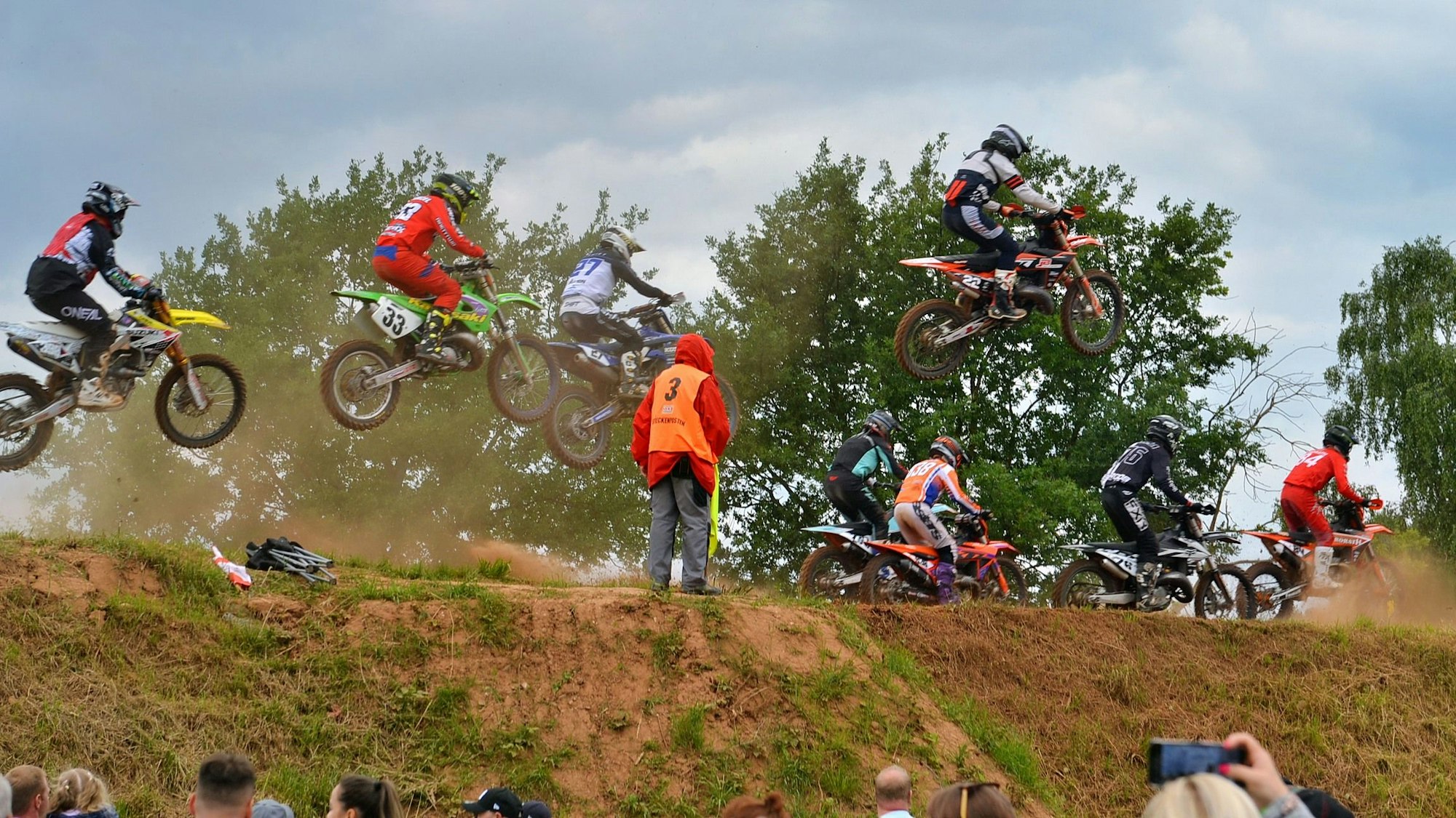 Motocross-Fahrer verlassen teil springend einen Hügel.