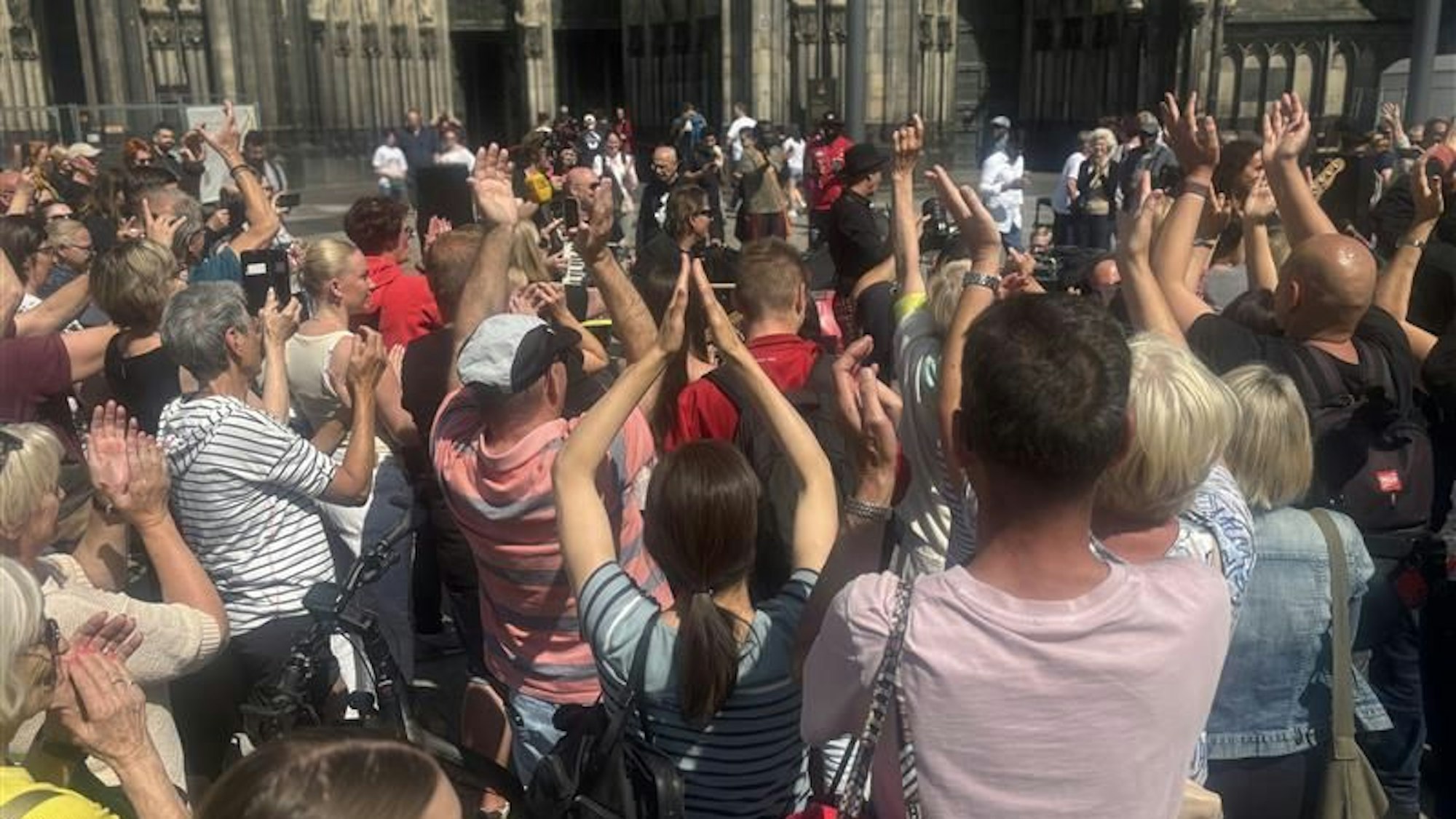 Zu sehen sind viele Menschen, die auf der Domplatte vor der Band Brings stehen, die gerade ein Konzert geben.