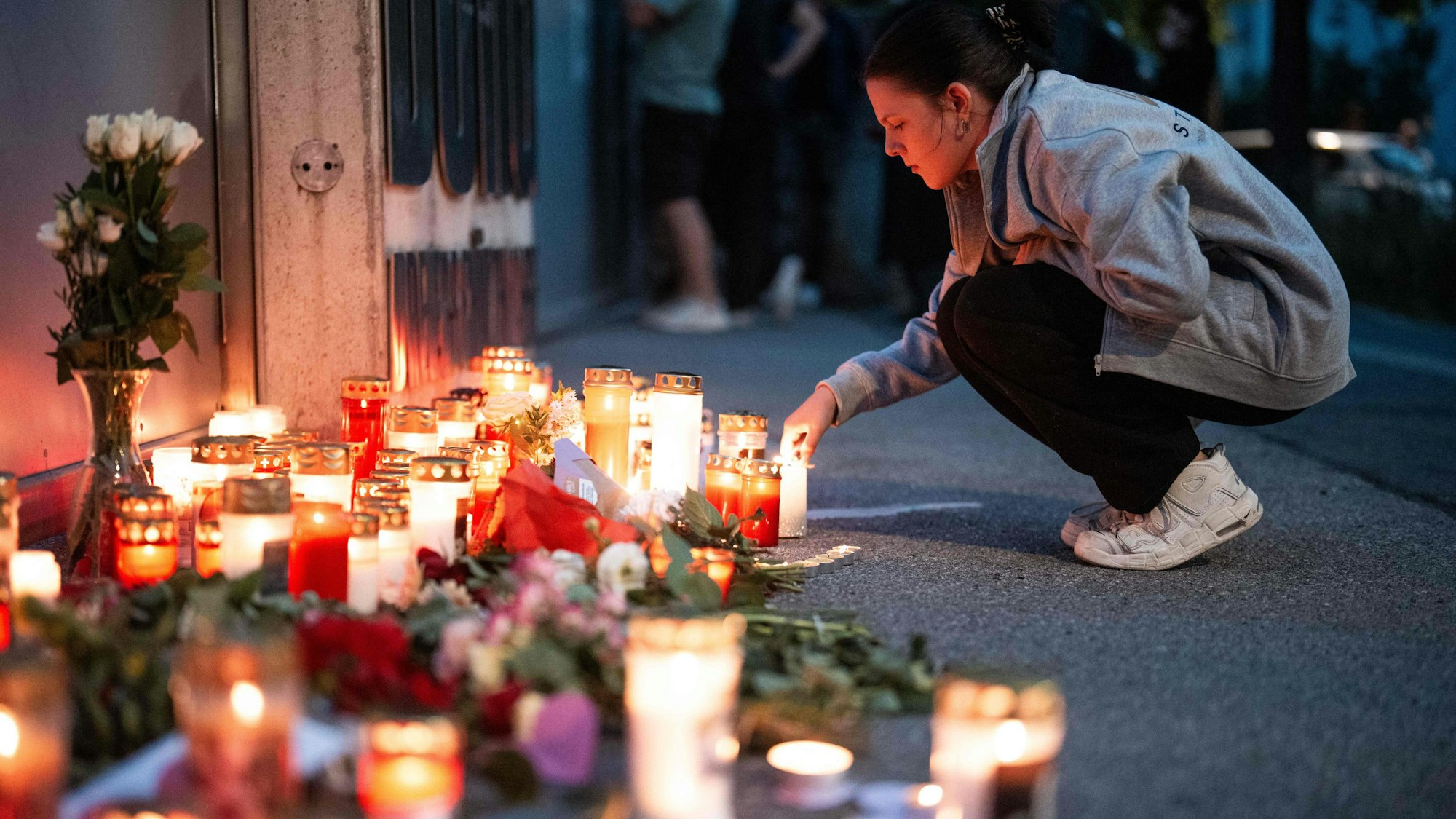 Eine Frau zündet eine Kerze im Gedenken an die Todesopfer des Amoklaufs vom Graz am 10. Juni 2025 an. Foto: Georg Hochmuth / AF