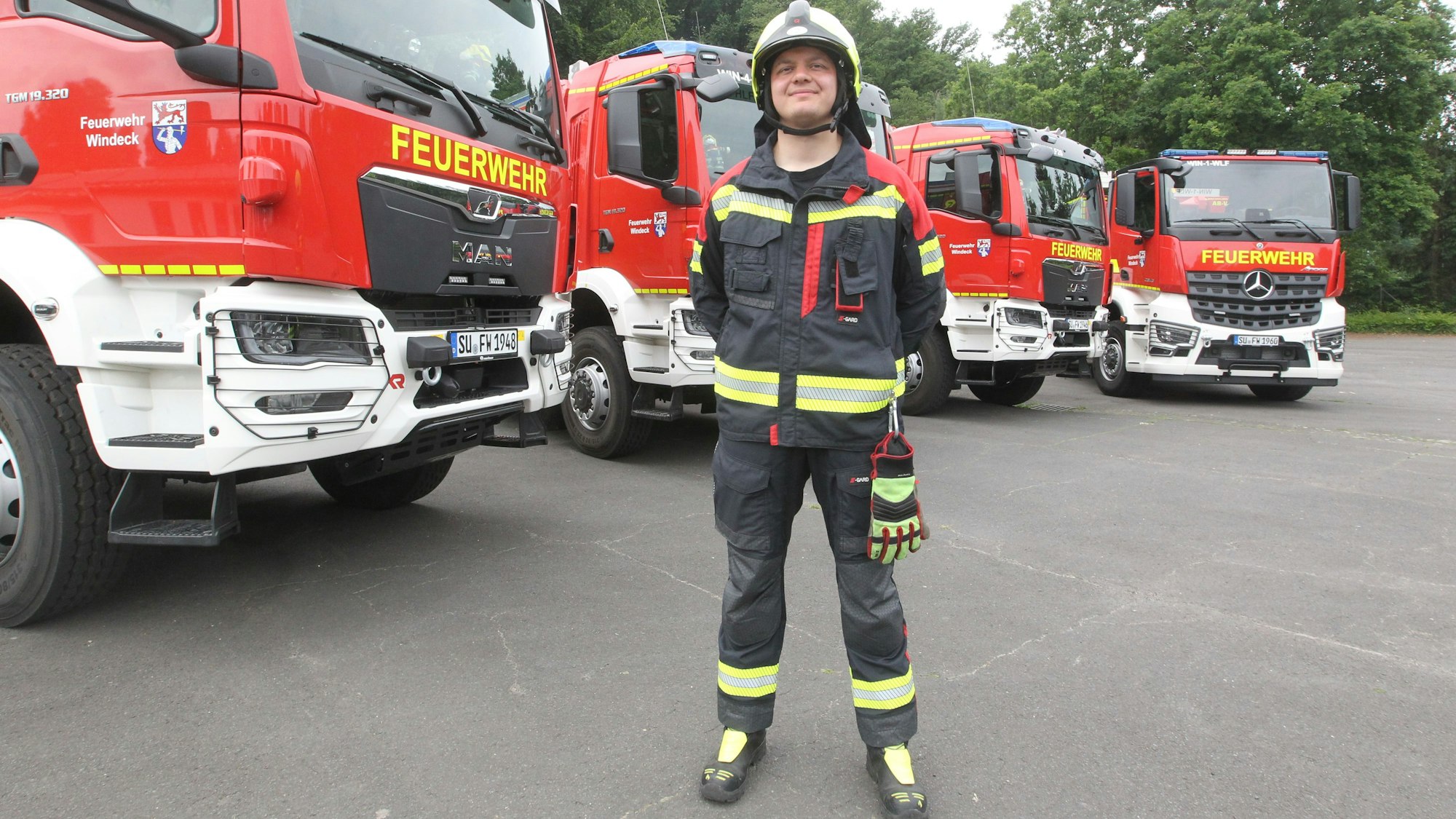 Feuerwehrmann Janos Voss in der modernen Montur vor den neuen Fahrzeugen.