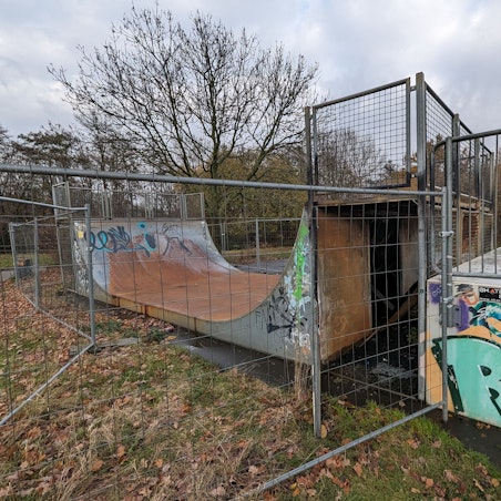 Das Foto zeigt die zerstörte Halfpipe hinter einem Bauzaun.