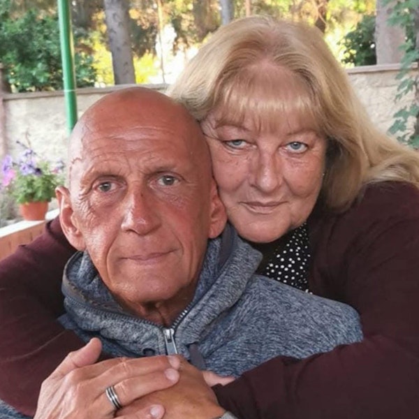 Auf dem Bild sind ein Mann und eine Frau zu sehen, die Frau legt die Arme um den Mann.