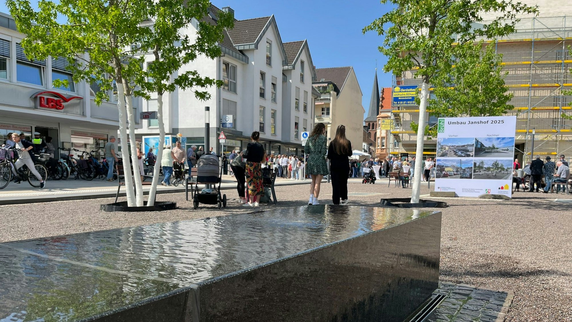 Zu sehen ist der Wassertisch und im Hintergrund der von einigen Passanten besuchte Platz.