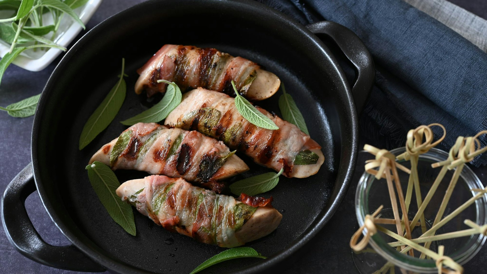 Ob in der Pfanne oder auf dem Grill: Umwickelt mit Salbeiblättern und Speck werden die Saltimbocca-Bratwürstchen garantiert zum Highlight.