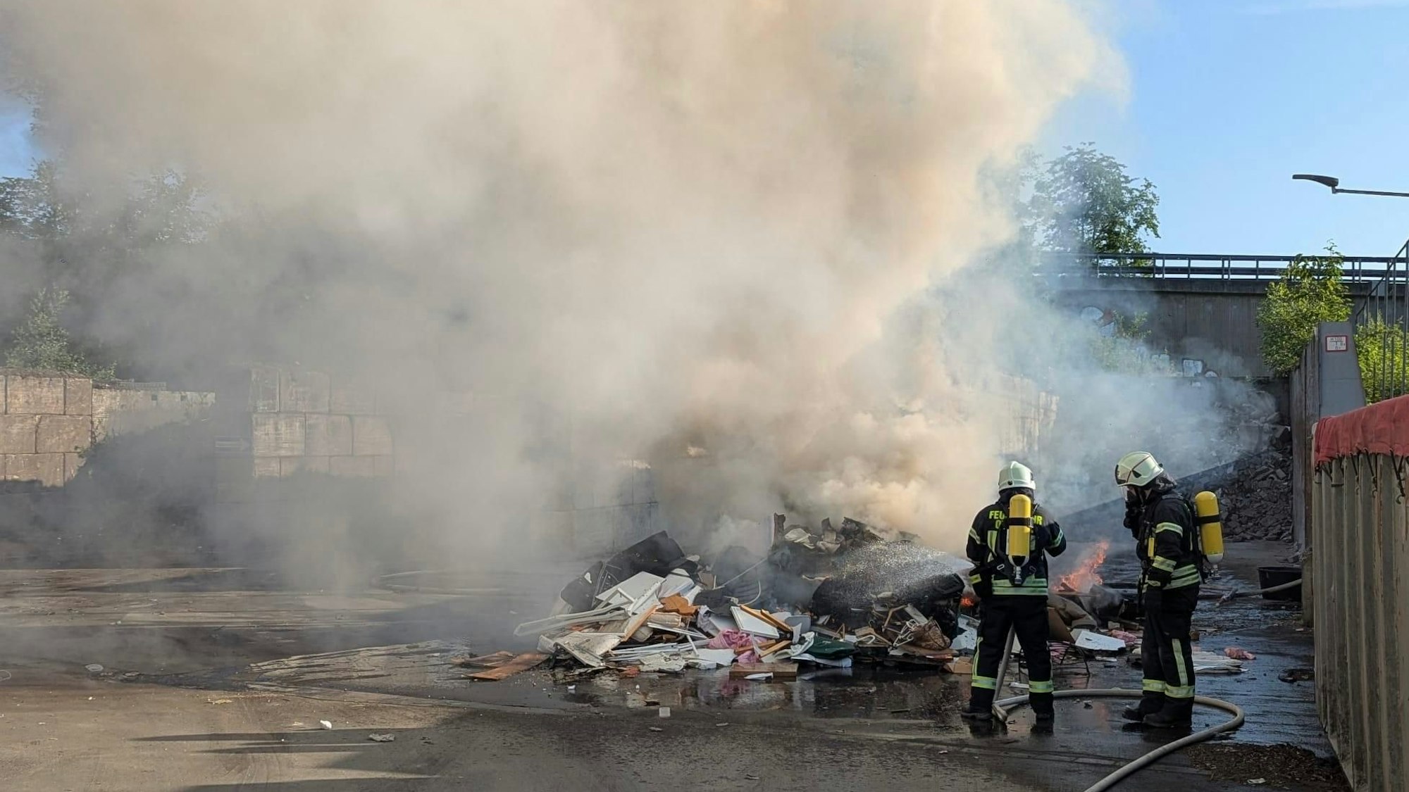 Feuerwehrleute löschen einen brennenden Müllhaufen.