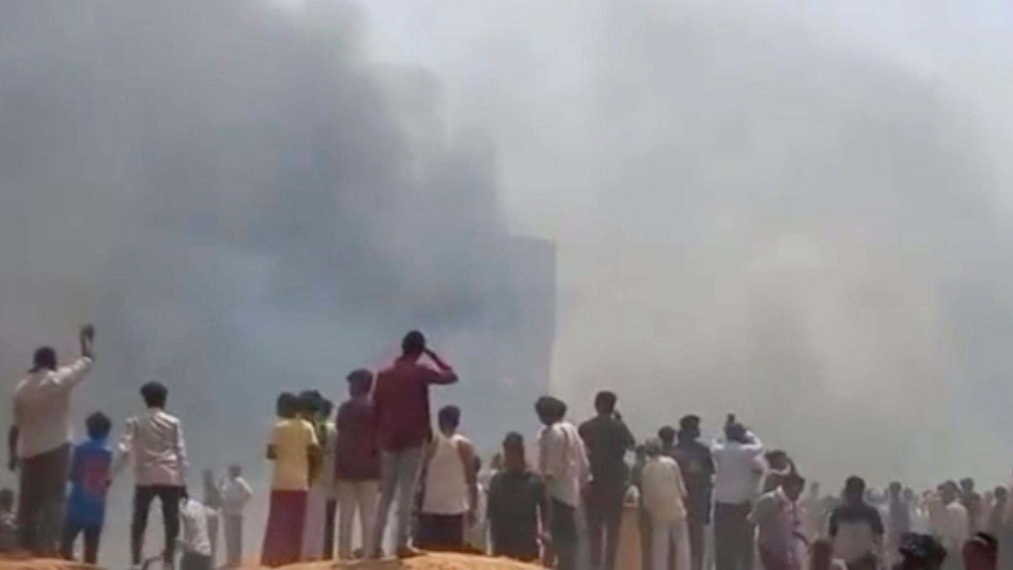 12.06.2025, Indien, Ahmedabad: *** VIDEOGRAB *** Menschen sehen Rauch aufsteigen, nachdem ein Flugzeug in Ahmedabad im indischen Bundesstaat Gujarat abgestürzt ist. Foto: Mohan Nakum/Mohan Nakum/AP/dpa - ACHTUNG: Nur zur redaktionellen Verwendung im Zusammenhang mit der aktuellen Berichterstattung und nur mit vollständiger Nennung des vorstehenden Credits +++ dpa-Bildfunk +++