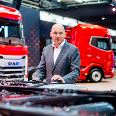 Auf dem Bild ist ein Mann vor roten Lkws zu sehen.