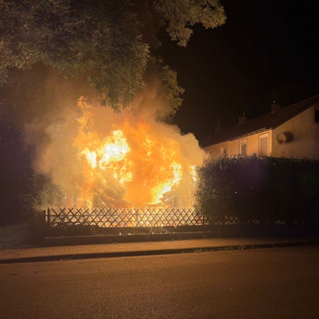 Eine brennende Gartenhütte im Garten eines Einfamilienhauses