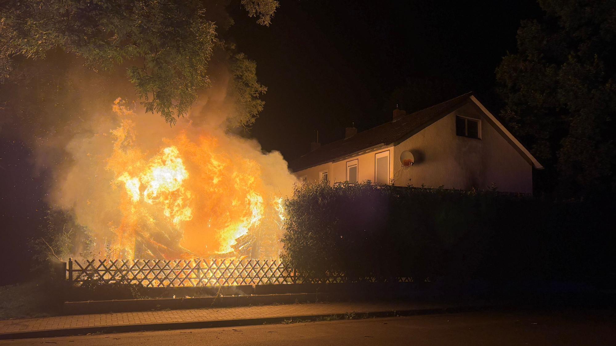 Eine brennende Gartenhütte im Garten eines Einfamilienhauses