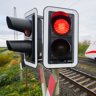 Eine rote Ampel leuchtet an einem Bahnübergang.