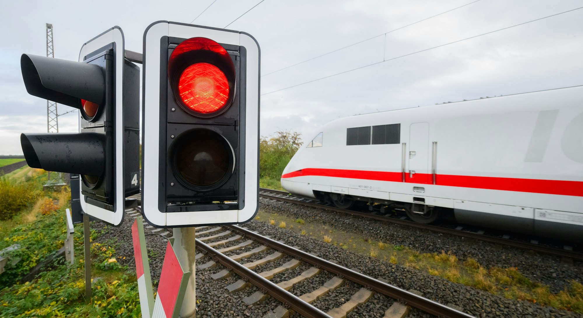 Eine rote Ampel leuchtet an einem Bahnübergang.