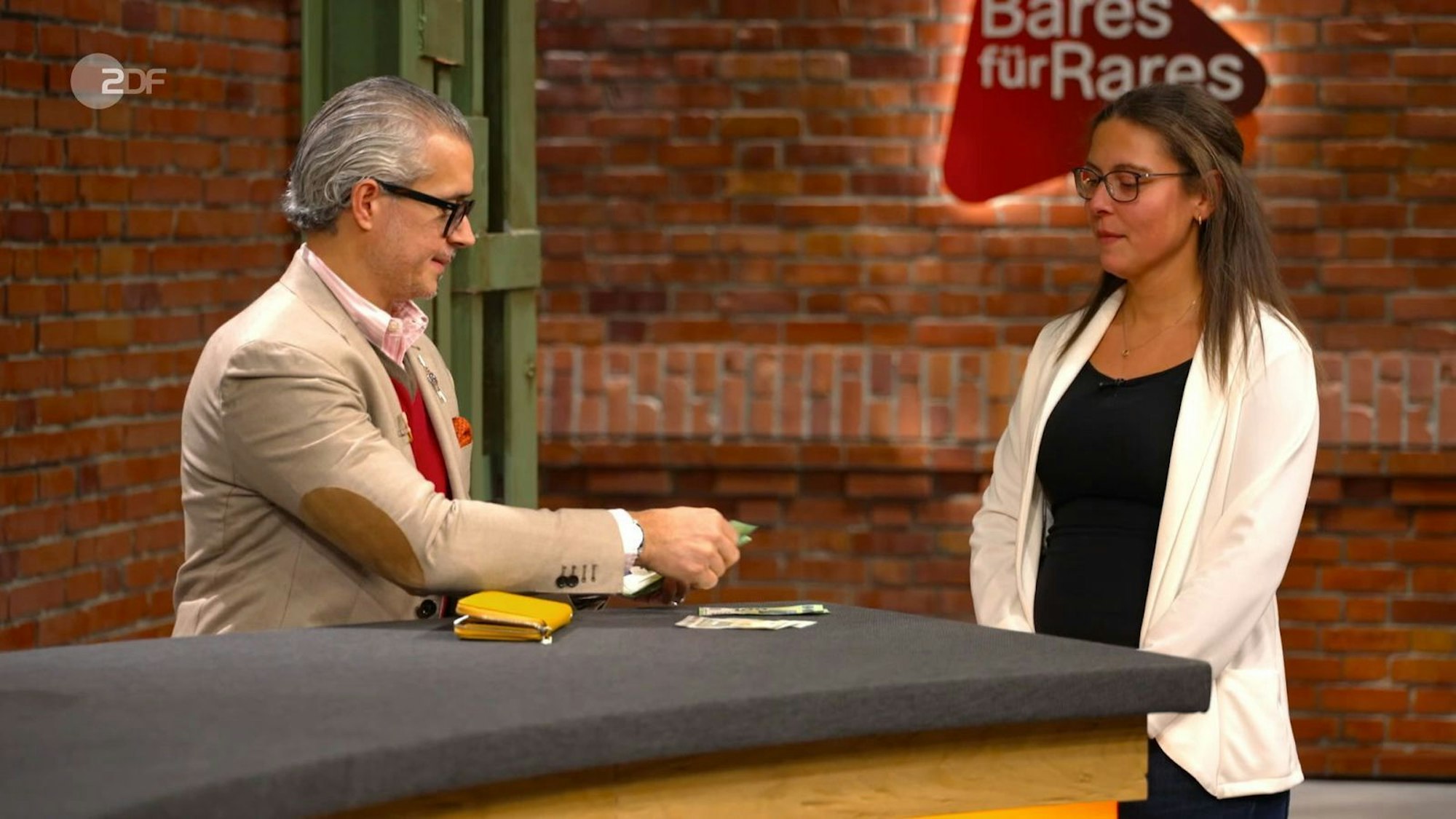 Die „Bares für Rares“-Händler ignorieren die Expertise einfach: Anaisio Guedes zahlt 1.020 Euro für das nachgemachte Werbeschild.
(Bild: ZDF)