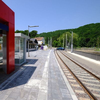 Der Haltepunkt in Urft erstrahlt in neuem Glanz. Im Hintergrund passiert ein blaues Auto den Bahnübergang.