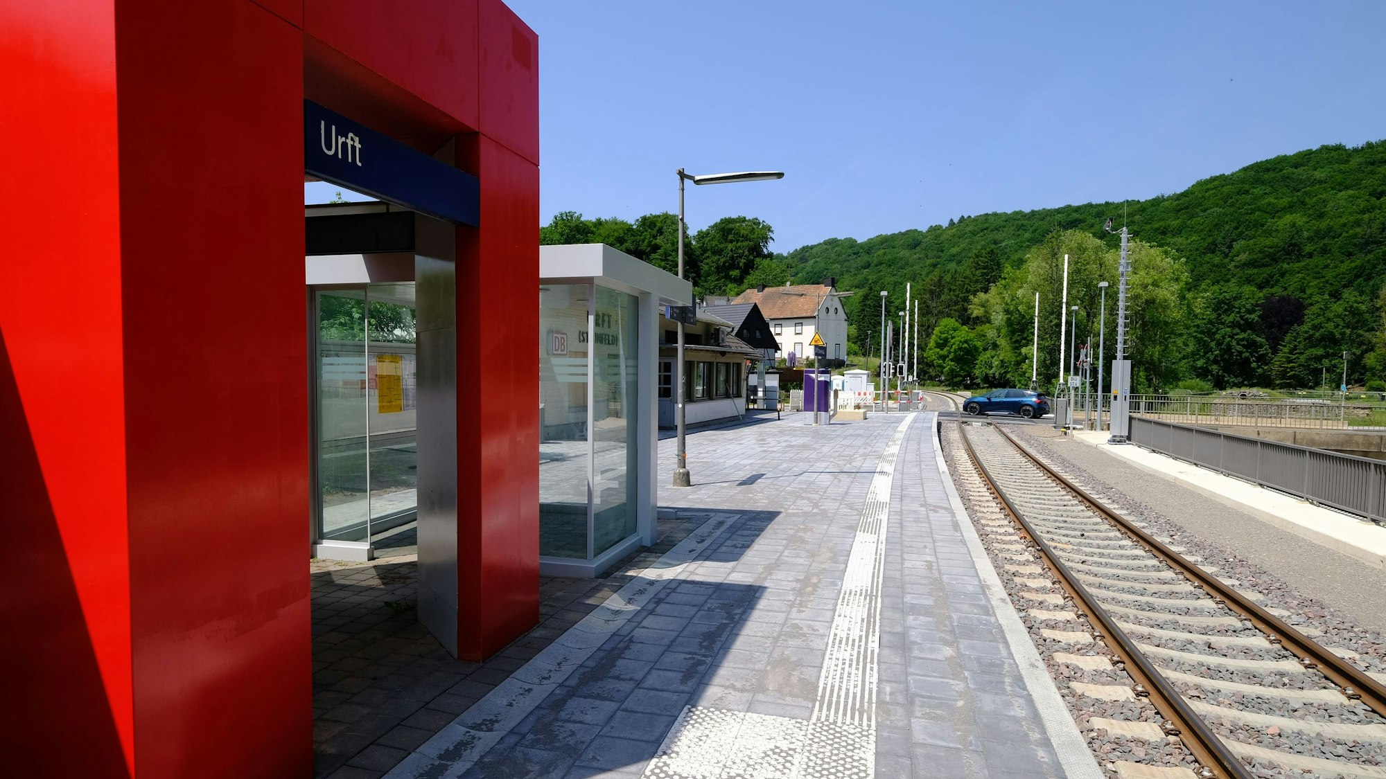 Der Haltepunkt in Urft erstrahlt in neuem Glanz. Im Hintergrund passiert ein blaues Auto den Bahnübergang.