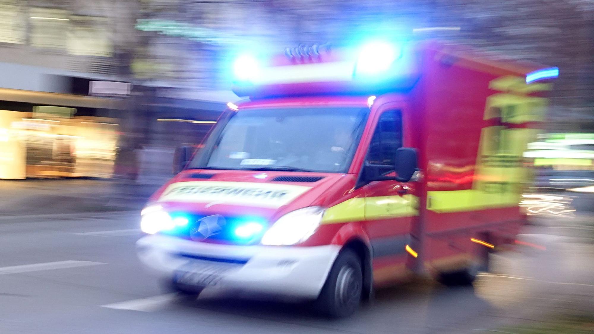 Ein Rettungswagen der Feuerwehr mit Blaulicht fährt eine Straße entlang. (Symbolbild)