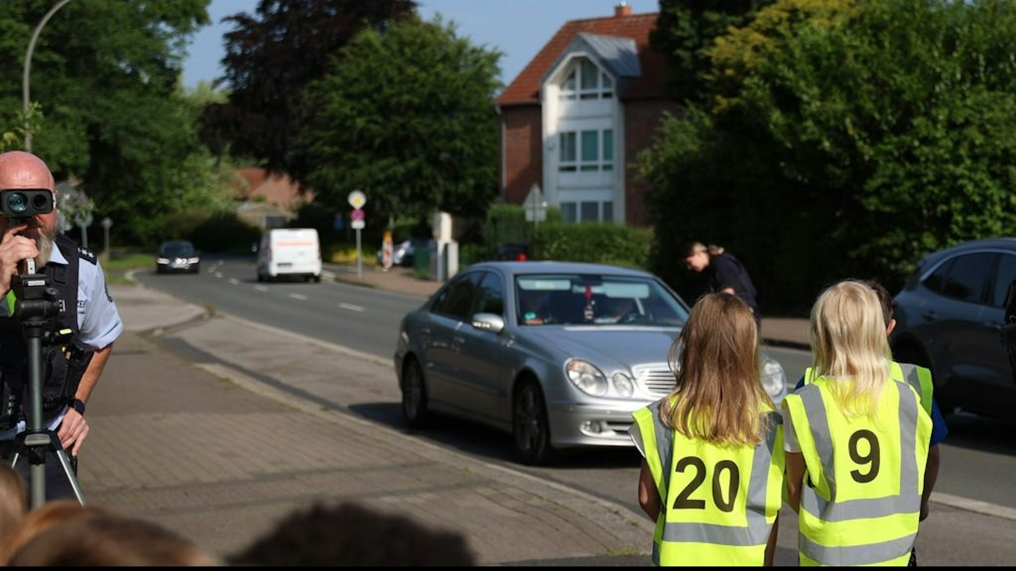 Verkehrssicherheitsaktion an der Urbanus Grundschule in Dorsten. Kinder in Warnwesten kontrollieren mit der Polizei die Geschwindigkeit von Fahrzeugen und verteilen Dank- und Denkzettel.