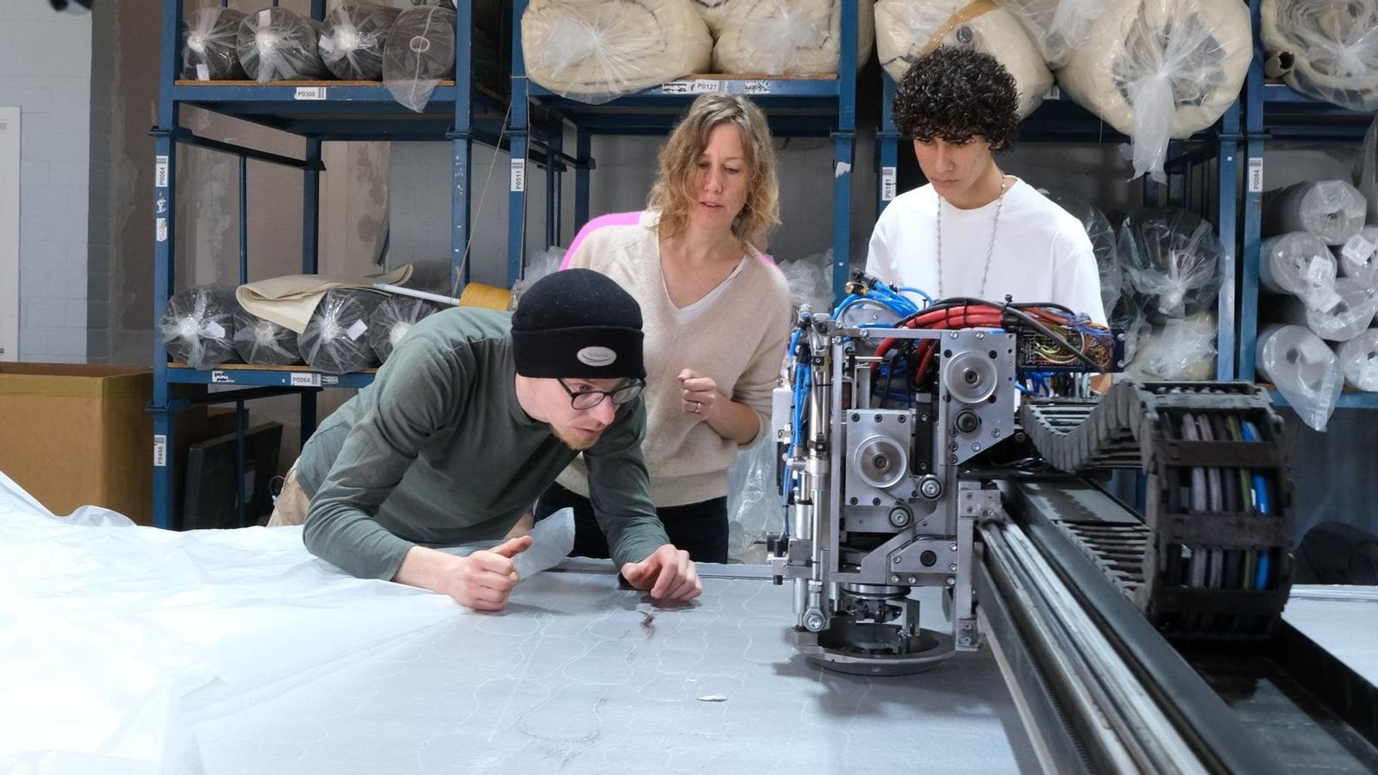 Bei Textilproduzent Marco Sheel (l.) prüfen Anna (M.) und Nevó Yona (r.) die Materialien für die Barfußschuhe.