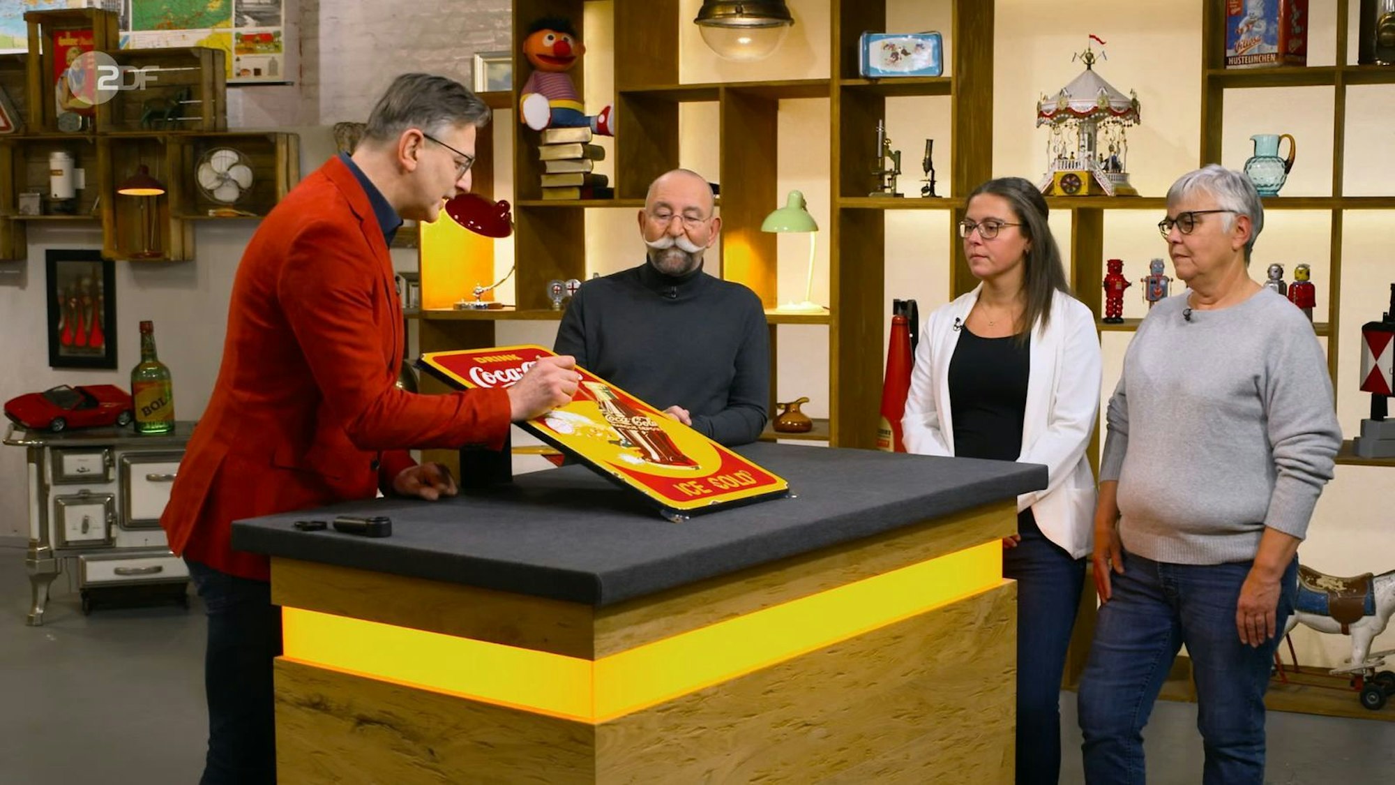 Das Werbeschild von Coca-Cola sieht aus wie aus den 1950er-Jahren. Doch „Bares für Rares“-Experte Detlev Kümmel deckt ein paar Unstimmigkeiten auf. (Bild: ZDF)