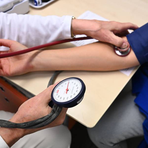 Ein Arzt misst in einer Bereitschaftspraxis in einem Krankenhaus in einem Untersuchungsraum bei einer Patientin den Blutdruck.
