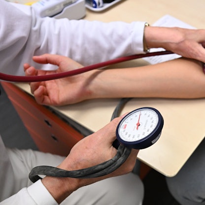 Ein Arzt misst in einer Bereitschaftspraxis in einem Krankenhaus in einem Untersuchungsraum bei einer Patientin den Blutdruck.