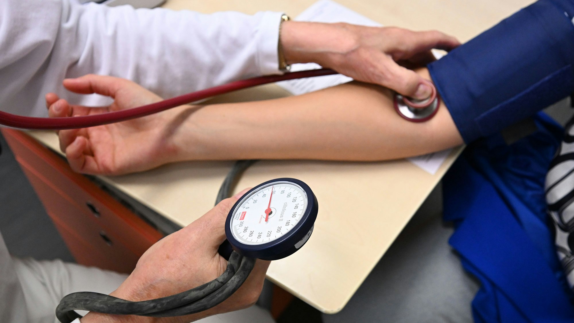 Ein Arzt misst in einer Bereitschaftspraxis in einem Krankenhaus in einem Untersuchungsraum bei einer Patientin den Blutdruck (gestellte Szene).