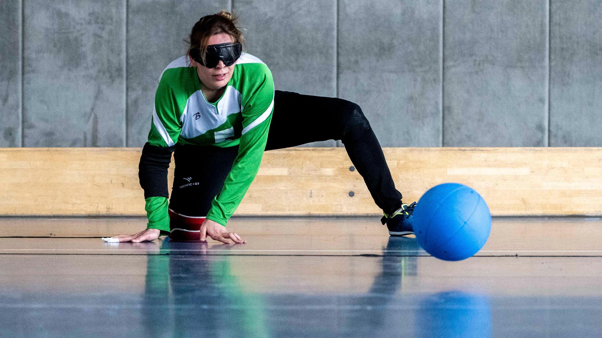 Das Bild zeigt eine Frau, die versucht, den blauen Hartgummiball zu antizipieren.