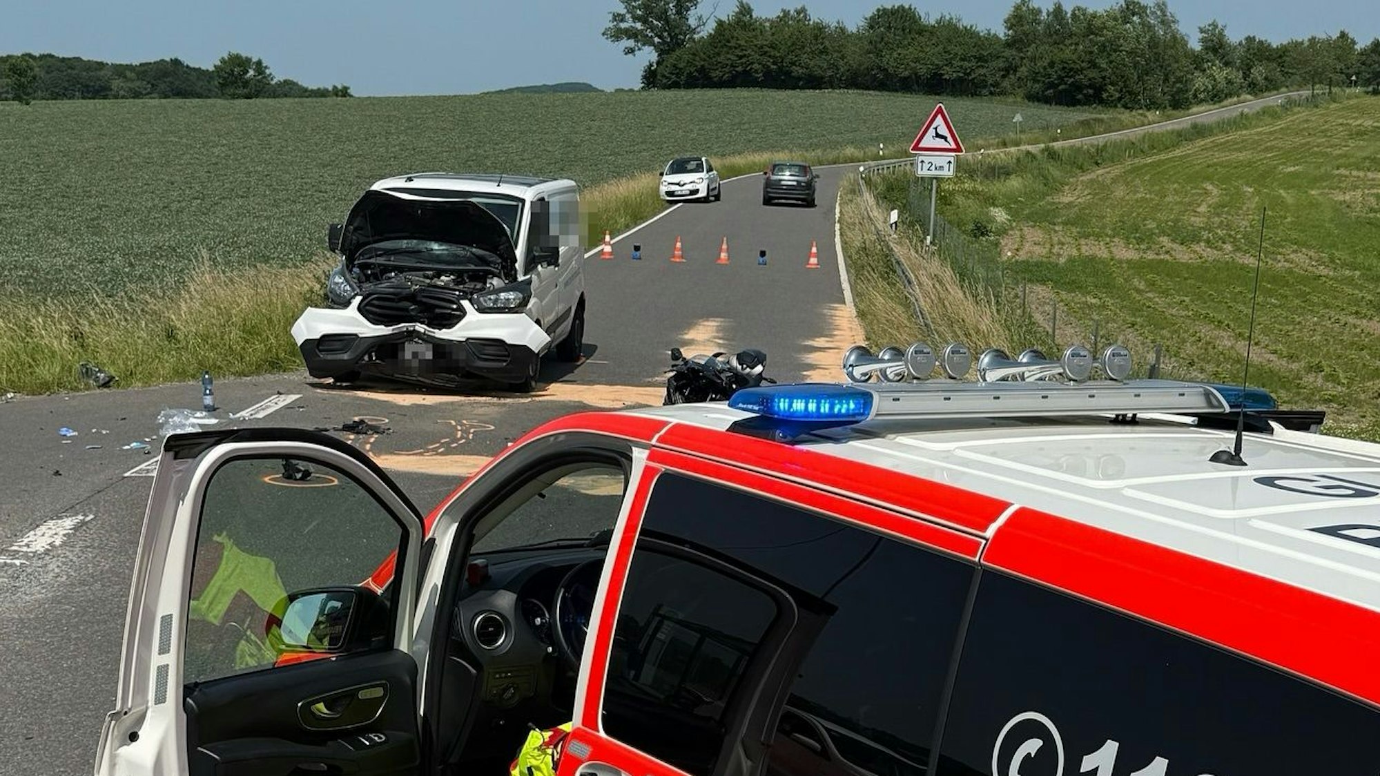 Ein Unfallauto steht auf der Landstraße 84 bei Overath. Im Vordergrund ist ein Notarzteinsatzfahrzeug zu sehen.